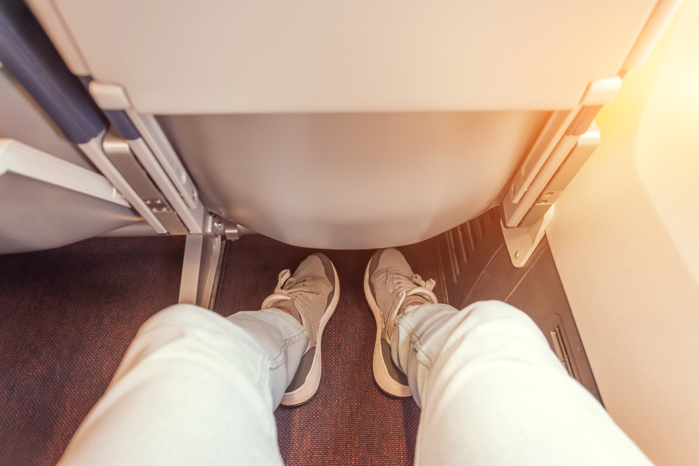 legs of woman sitting in airplane seat