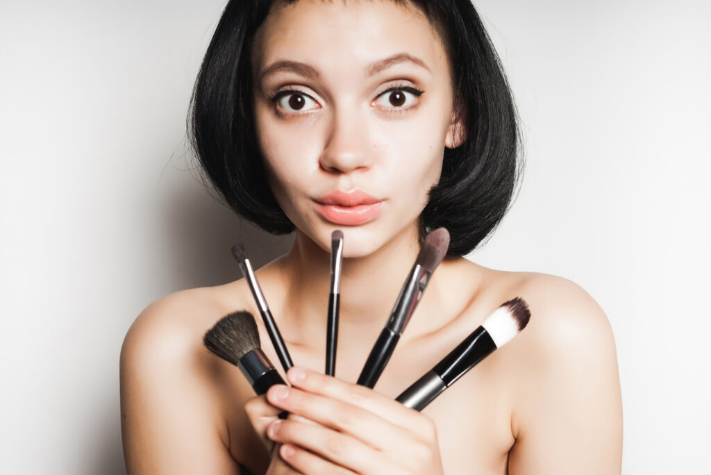 Woman with natural beauty holding makeup brushes.