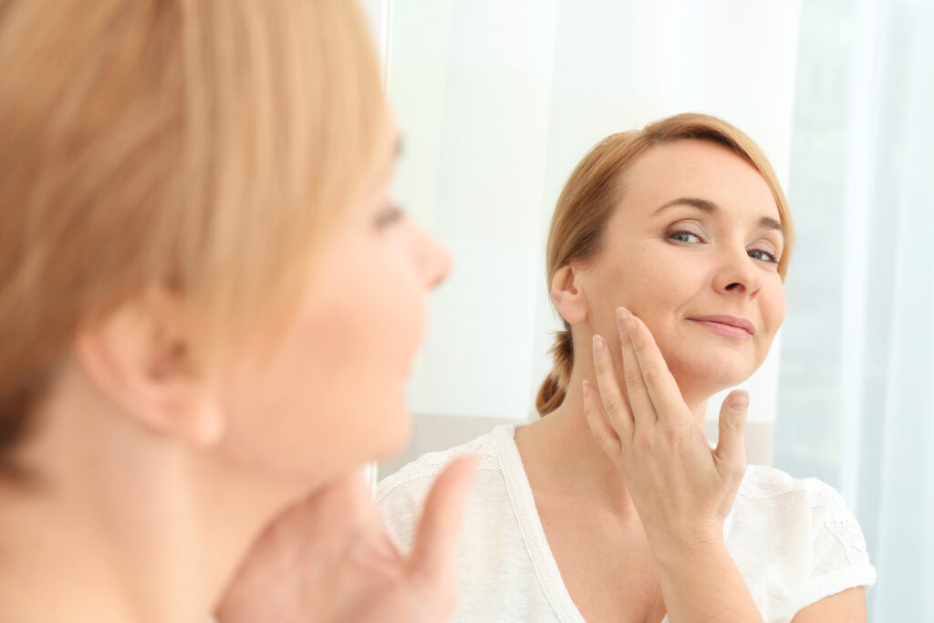 Woman looking in mirror at smooth skin after thread lift 