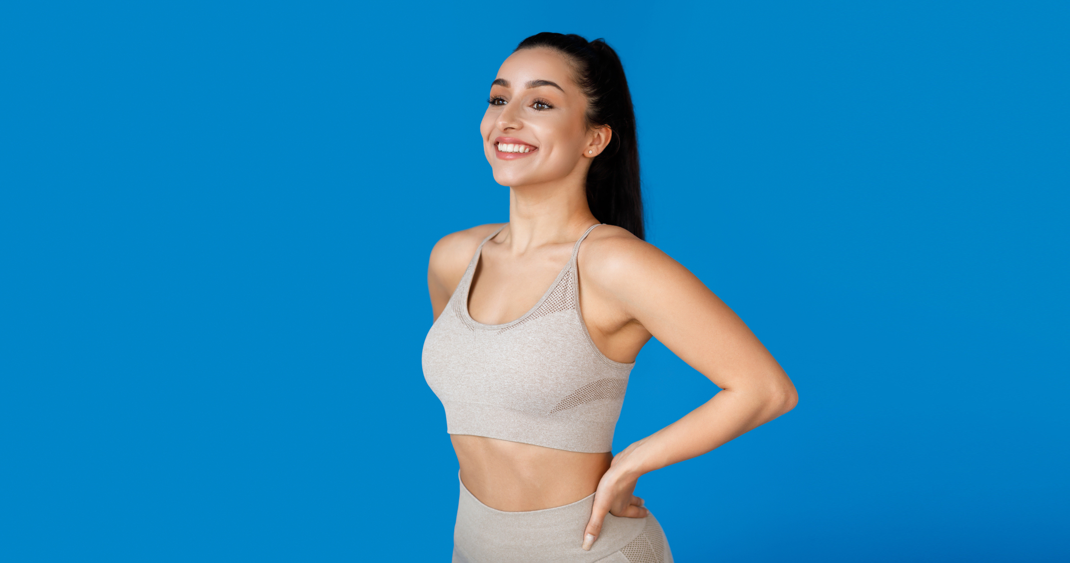 Happy woman with athletic body holding hands on waist